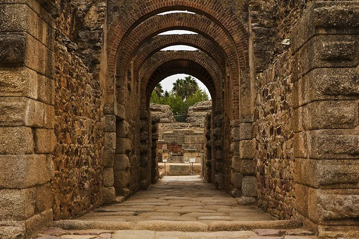 Galería abovedada de acceso al anfiteatro romano de Mérida con arcos de piedra y ladrillo.