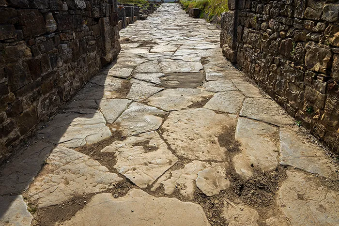 Calle empedrada de Baelo Claudia entre antiguos muros romanos.