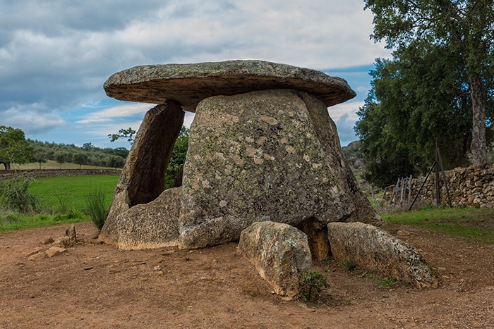 El Dolmen del Mellizo visto desde un ángulo diagonal, resaltando la forma de su entrada y el túmulo de tierra erosionado.