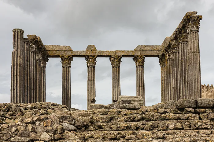 Vista posterior del templo romano de Évora con el podio de piedra en primer plano y columnas corintias al fondo.