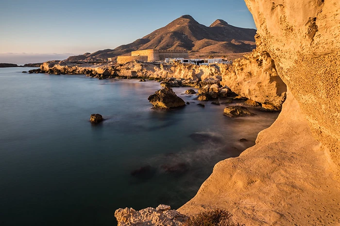 Vista panorámica del Castillo de San Felipe y la costa de Los Escullos bañados en luz dorada.
