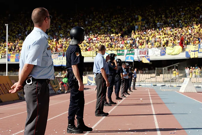 Vigilantes de seguridad junto a agentes de la Policía Nacional dentro de un estadio de fútbol.