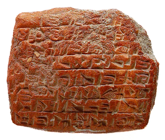 Tablilla de arcilla rojiza con escritura cuneiforme sumeria, texto breve en líneas horizontales.