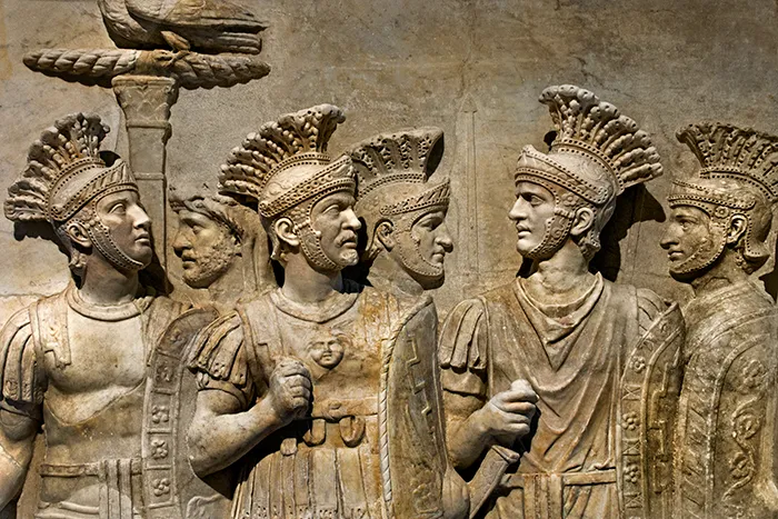 Relieve romano con varios soldados pretorianos vestidos con armaduras y cascos ornamentados.