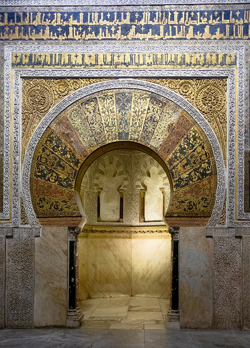 Vista frontal del mihrab de la Mezquita Catedral de Córdoba con arco decorado en mosaicos bizantinos y caligrafía cúfica dorada.