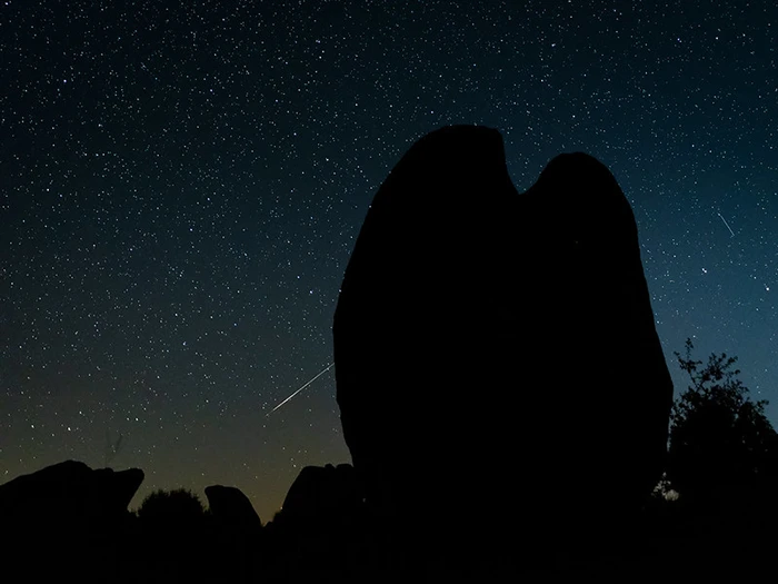 Silueta de gran bolo granítico en Los Barruecos con estrella fugaz al fondo.