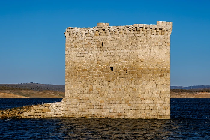 Detalle frontal de la Torre de Floripes, destacando su arquitectura gótica sobre el agua en un día despejado